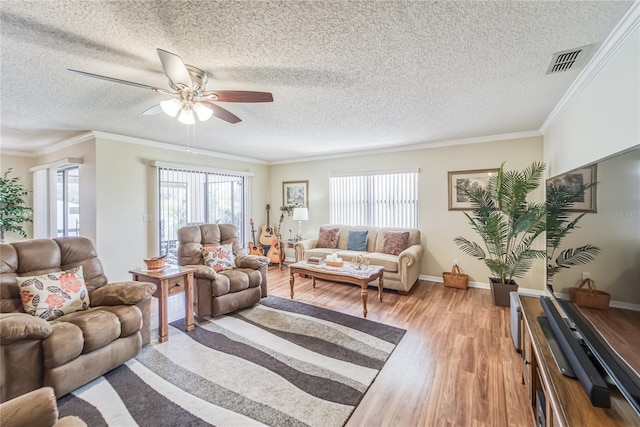 living room featuring a textured ceiling, light wood-type flooring, ceiling fan, and crown molding