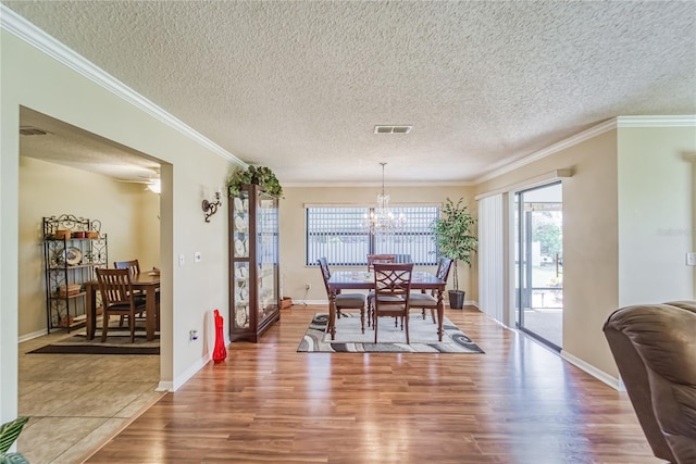 dining space featuring wood-type flooring, a textured ceiling, and ornamental molding