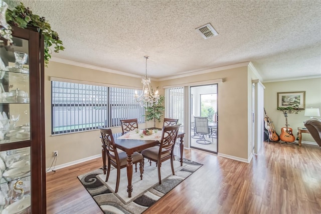 dining room featuring a textured ceiling, light wood-type flooring, and crown molding