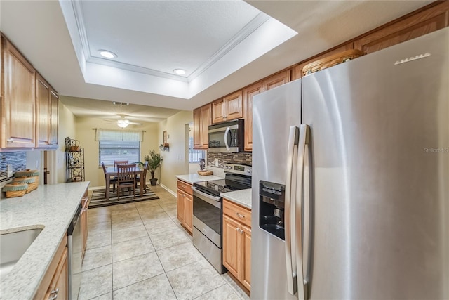 kitchen featuring light tile patterned floors, backsplash, stainless steel appliances, and a raised ceiling