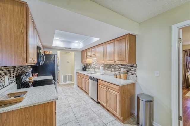 kitchen with backsplash, light stone counters, stainless steel appliances, a tray ceiling, and sink