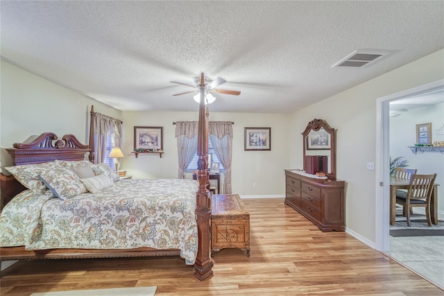 bedroom with a textured ceiling, light hardwood / wood-style floors, and ceiling fan