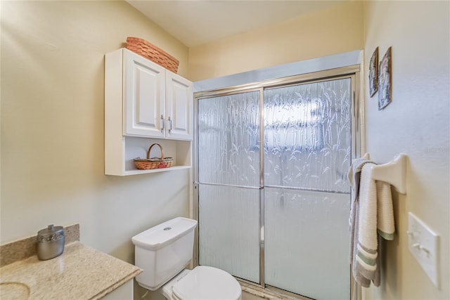 bathroom with vanity, toilet, and a shower with door