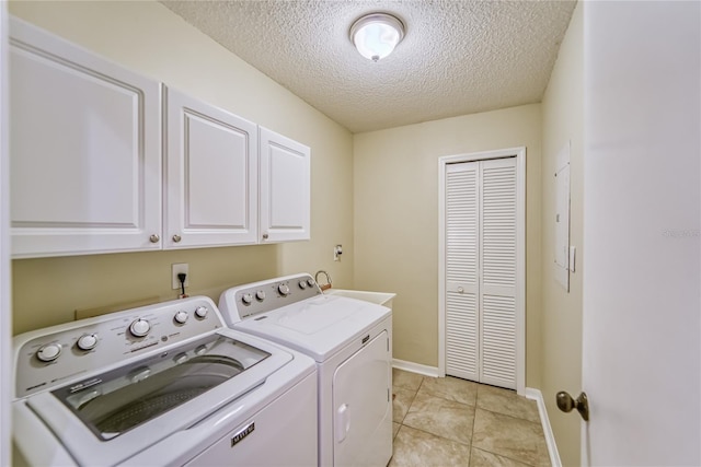 laundry room with light tile patterned floors, cabinets, a textured ceiling, and independent washer and dryer