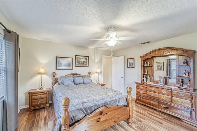 bedroom featuring ceiling fan, light hardwood / wood-style floors, and a textured ceiling