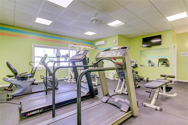 exercise room featuring a paneled ceiling and a wall mounted air conditioner