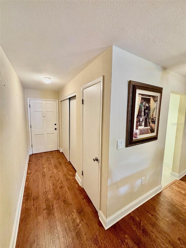 hall with hardwood / wood-style floors and a textured ceiling