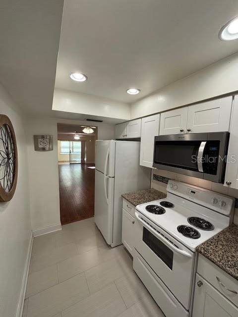 kitchen with recessed lighting, white appliances, white cabinetry, a ceiling fan, and dark stone countertops