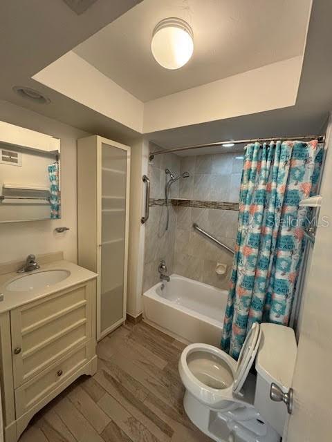 bathroom with shower / bath combination with curtain, vanity, toilet, and wood finished floors