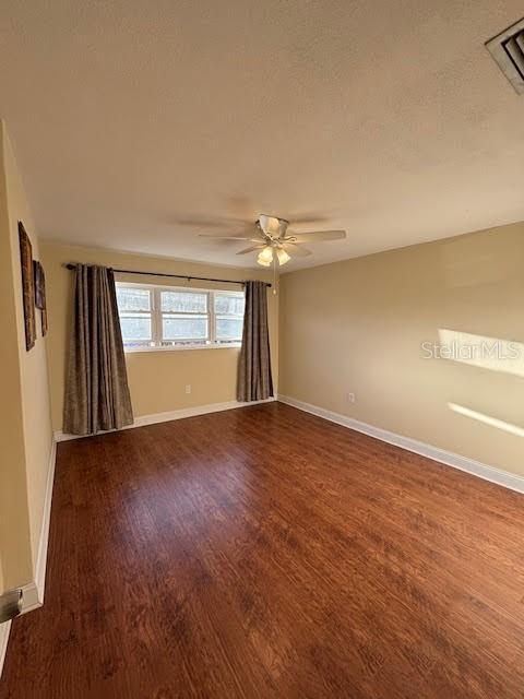 spare room with visible vents, ceiling fan, baseboards, and wood finished floors