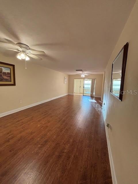 unfurnished room featuring ceiling fan, dark wood finished floors, and baseboards