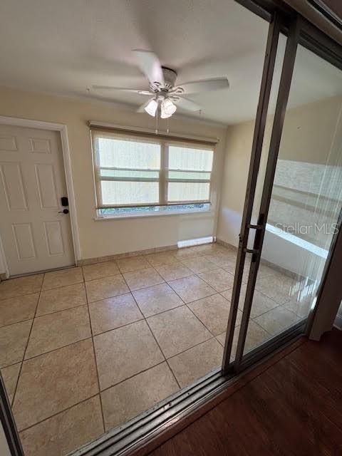 doorway to outside with light tile patterned floors, ceiling fan, and baseboards