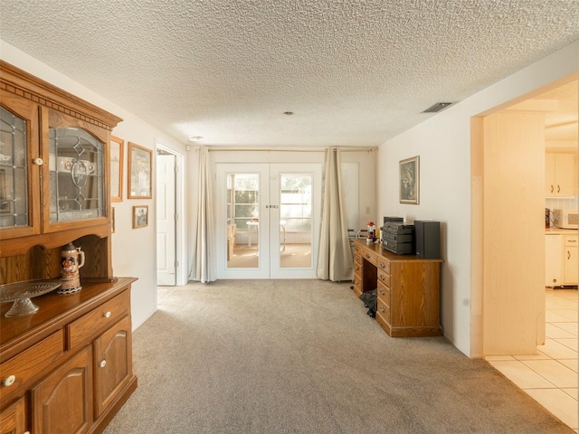 interior space featuring light carpet, french doors, and a textured ceiling