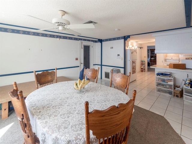 tiled dining area with a textured ceiling and ceiling fan