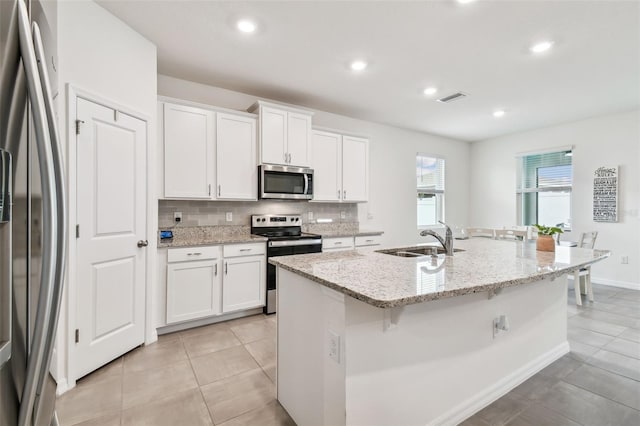 kitchen with white cabinets, stainless steel appliances, a center island with sink, and sink