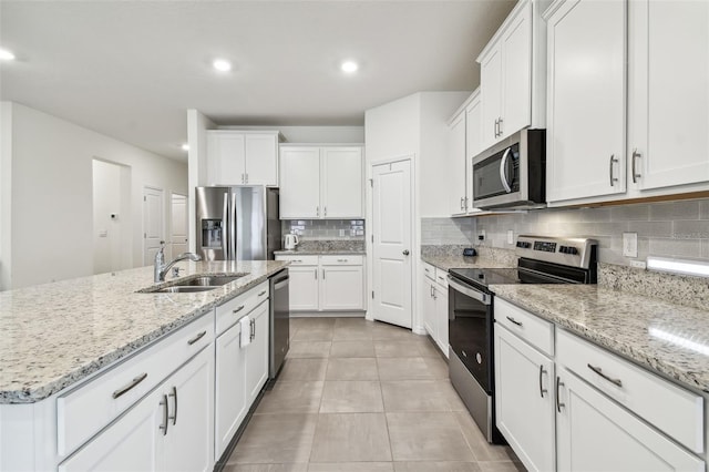 kitchen with white cabinets, appliances with stainless steel finishes, an island with sink, and sink