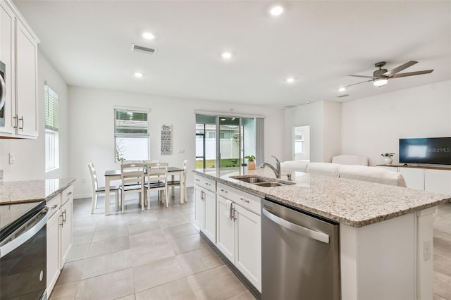 kitchen featuring dishwasher, a kitchen island with sink, white cabinets, sink, and black electric range