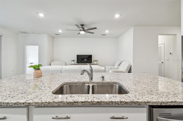 kitchen featuring light stone countertops, sink, and a kitchen island with sink