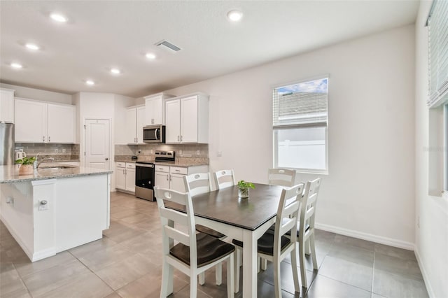 kitchen with backsplash, sink, white cabinets, and stainless steel appliances