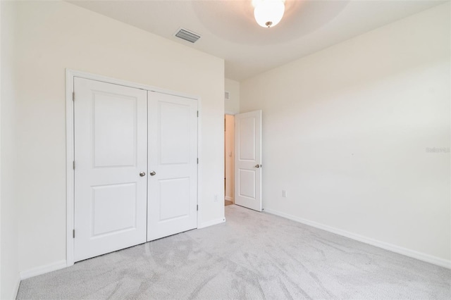 unfurnished bedroom with ceiling fan, light colored carpet, and a closet