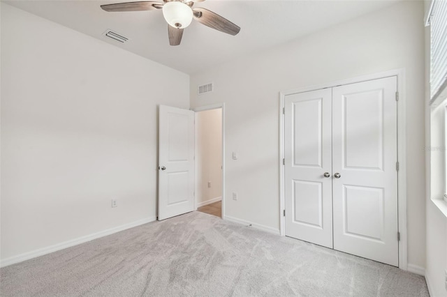 unfurnished bedroom featuring ceiling fan, a closet, and light carpet