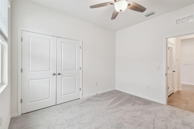 unfurnished bedroom with light carpet, a closet, and ceiling fan