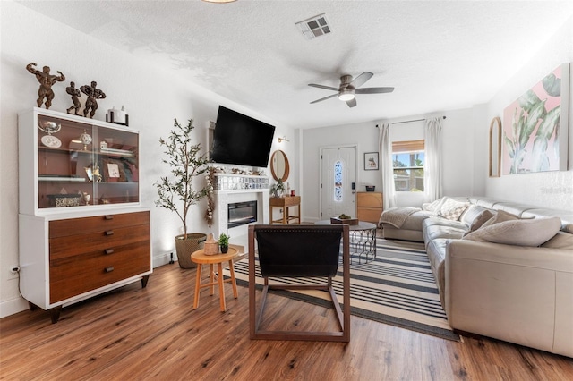 living room with ceiling fan, hardwood / wood-style floors, and a textured ceiling