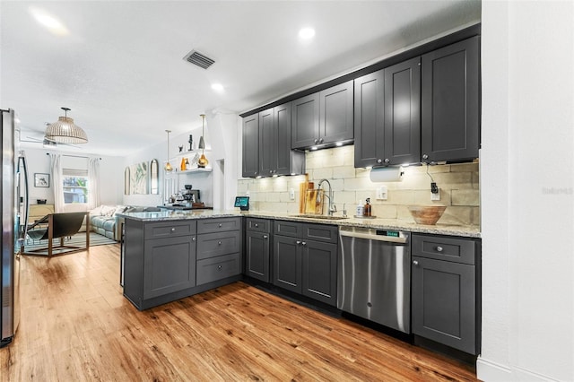 kitchen with sink, light hardwood / wood-style flooring, decorative light fixtures, and appliances with stainless steel finishes