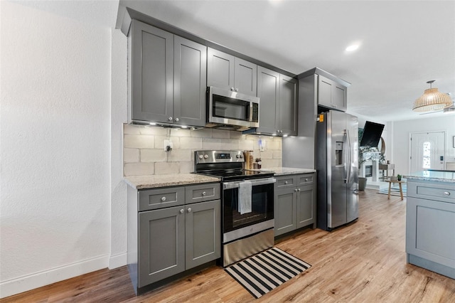 kitchen with gray cabinets, light stone counters, light hardwood / wood-style flooring, and appliances with stainless steel finishes