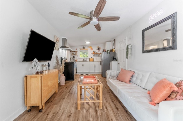 living room with light hardwood / wood-style flooring, ceiling fan, lofted ceiling, and sink