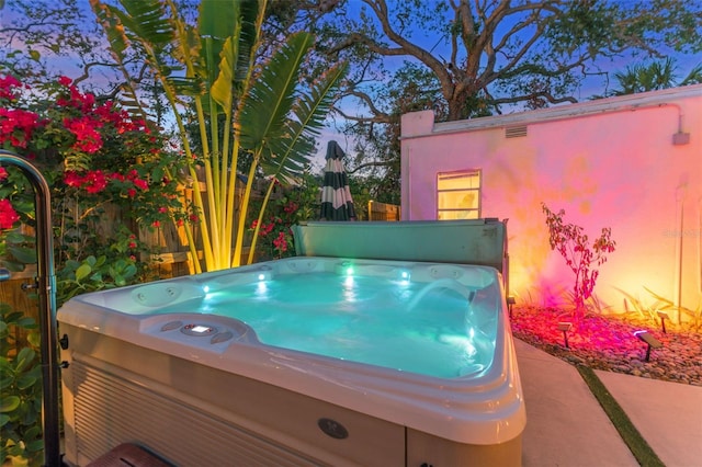 pool at dusk with a hot tub