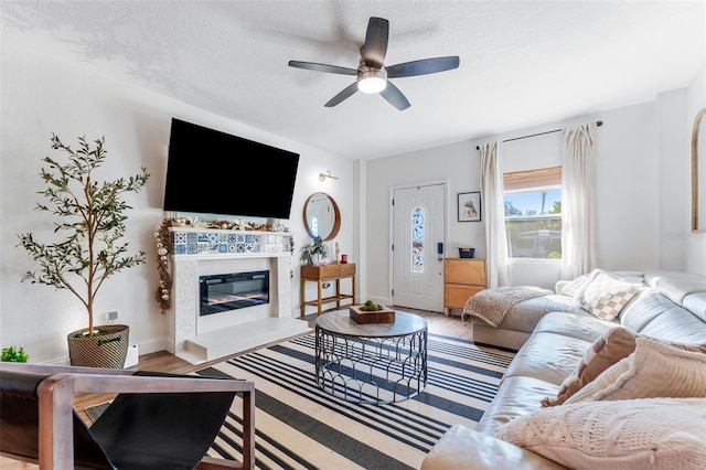 727 53rd Ter N, Saint Petersburg, FL 33703 - living room with wood finished floors, baseboards, ceiling fan, a textured ceiling, and a tiled fireplace