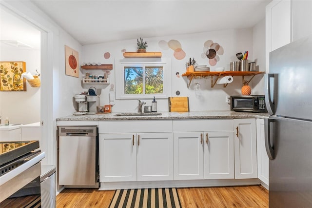 727 53rd Ter N, Saint Petersburg, FL 33703 - kitchen with open shelves, a sink, stainless steel appliances, white cabinetry, and light wood-type flooring