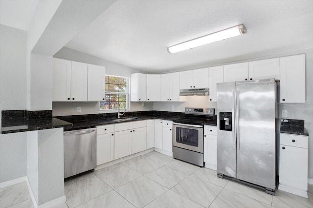 kitchen with white cabinets, sink, vaulted ceiling, dark stone countertops, and appliances with stainless steel finishes