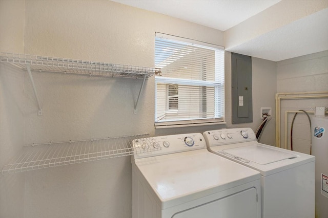 washroom featuring electric panel, washer and clothes dryer, and a healthy amount of sunlight