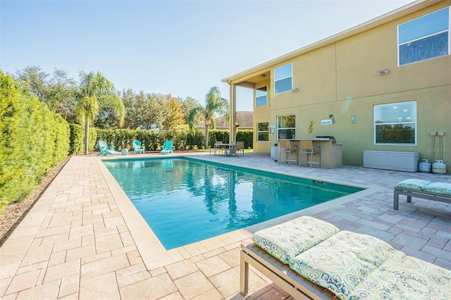 view of swimming pool with an outdoor bar and a patio