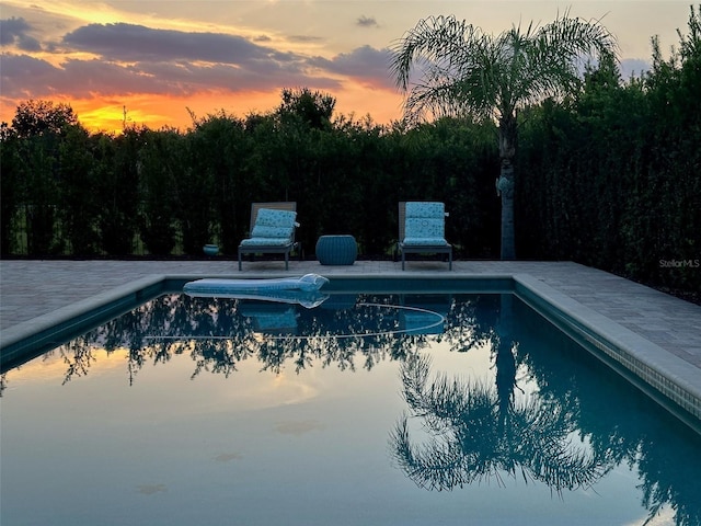 pool at dusk featuring a patio