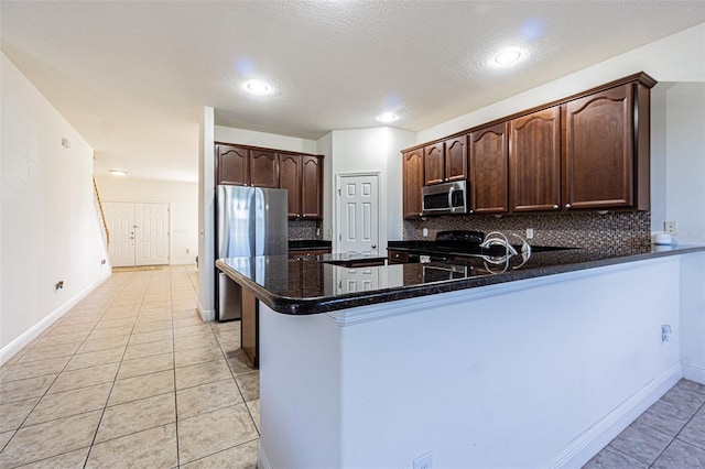 kitchen with backsplash, kitchen peninsula, dark brown cabinetry, and stainless steel appliances