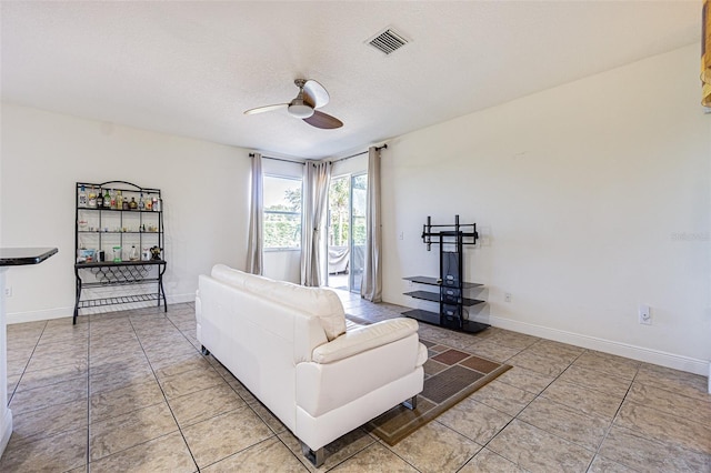 living room featuring tile patterned flooring, ceiling fan, and a textured ceiling