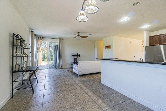 unfurnished living room featuring ceiling fan, light tile patterned flooring, and a textured ceiling