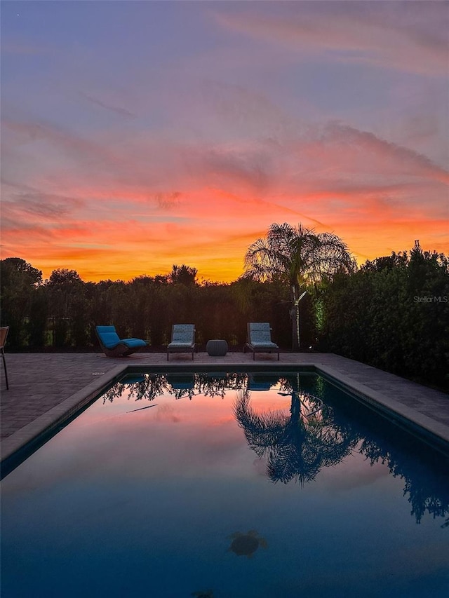 pool at dusk featuring a patio area