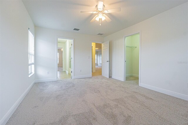 5709 White Trillium Loop, Land O Lakes, FL 34639 - unfurnished bedroom with a spacious closet, light carpet, baseboards, and ceiling fan