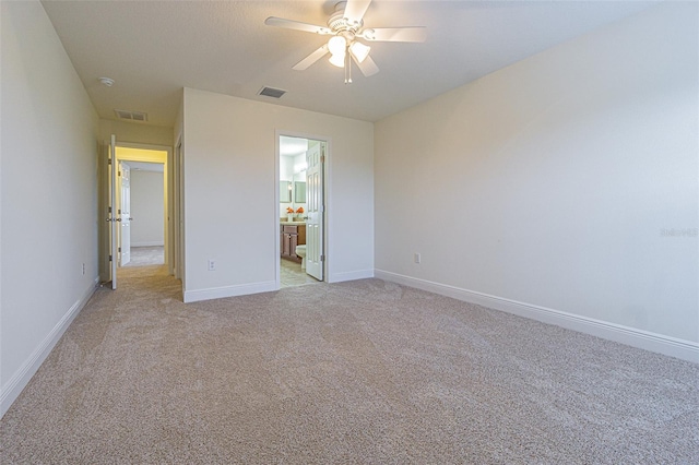 5709 White Trillium Loop, Land O Lakes, FL 34639 - unfurnished bedroom with light colored carpet, baseboards, ceiling fan, and connected bathroom