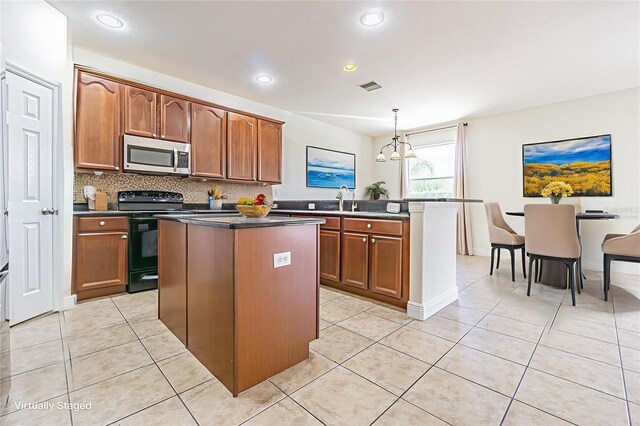 5709 White Trillium Loop, Land O Lakes, FL 34639 - kitchen featuring stainless steel microwave, black range with electric stovetop, a kitchen island, light tile patterned floors, and dark countertops