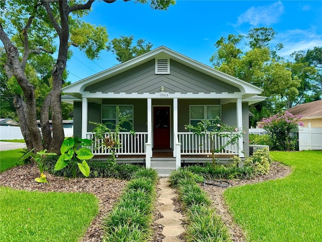 view of front facade with a porch, a front yard, and fence