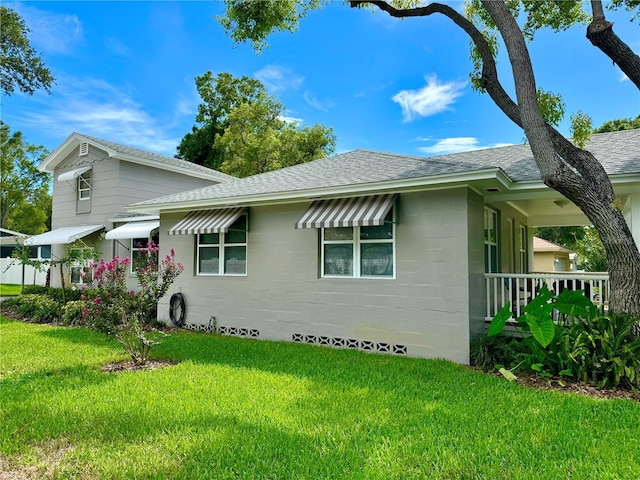 view of front of home with a front lawn, concrete block siding, and a shingled roof