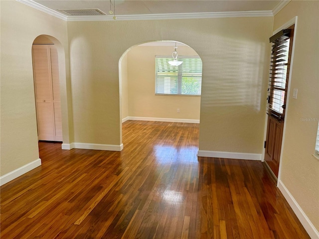 1003 Beverly Ave, Largo, FL 33770 - spare room featuring crown molding, arched walkways, hardwood / wood-style flooring, and baseboards