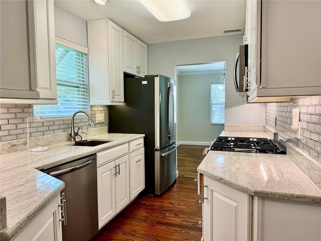 1003 Beverly Ave, Largo, FL 33770 - kitchen with stainless steel appliances, a sink, dark wood-style floors, tasteful backsplash, and white cabinetry