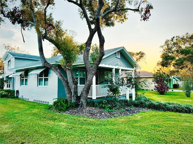 view of front of property with a porch and a yard