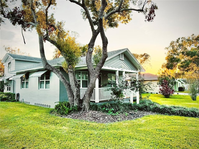 view of front of property with covered porch, a shingled roof, and a front yard